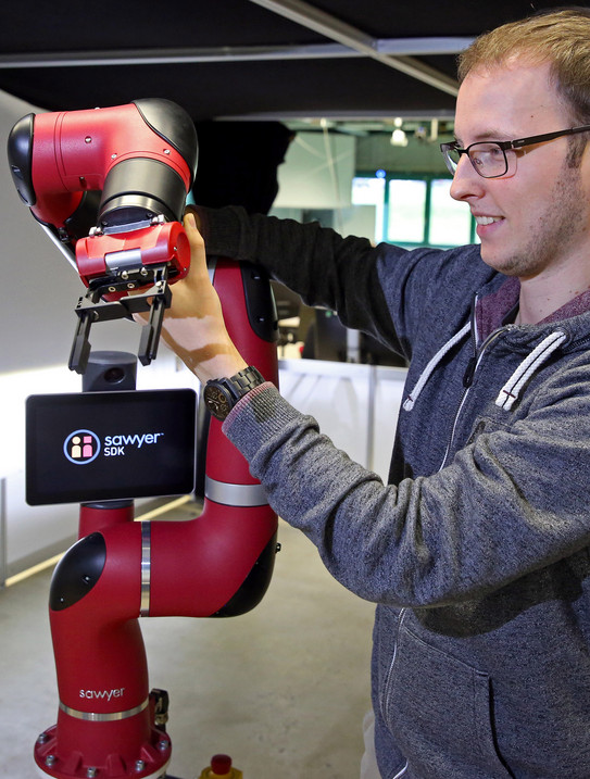 Junger Mann bedient einen Roboterarm Junger Mann bedient einen Roboterarm
