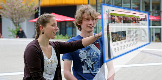Studenten, junge Frau und junger Mann, vor Projektionsfläche