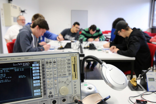 Messen und sichtbar machen von Funkwellen Schülerinnen und Schüler beim experimentellen Löten, Messgerät im Vordergrund