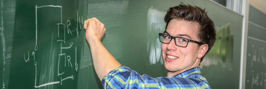 Ein Student schreibt eine mathematische Gleichung an eine Tafel