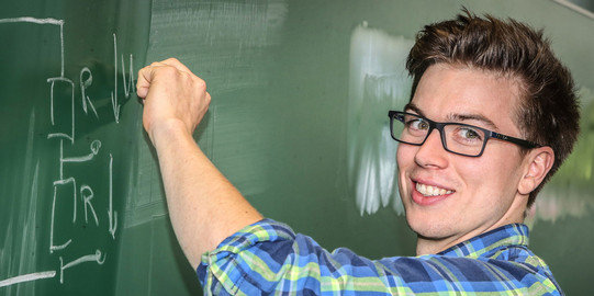 Student vor Tafel Ein Student schreibt eine mathematische Gleichung an eine Tafel