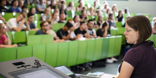 Dozierende sitzt vor Studierenden im Hörsaal im Seminargebäude. 